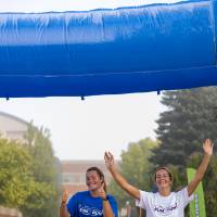 Two participants, smiling, finish the course. One with their hands in the air.